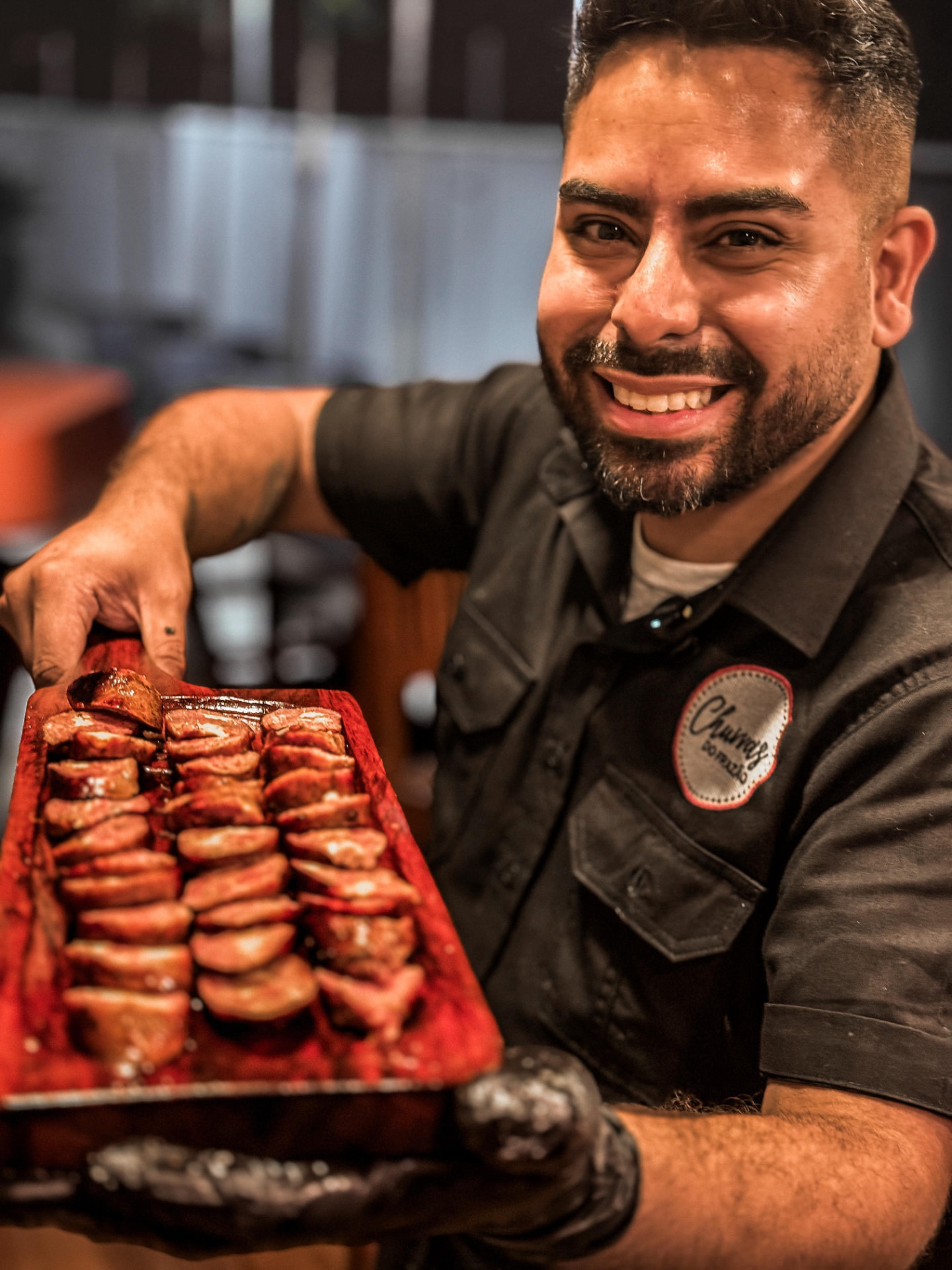 Frazão sorrindo e servindo tábua de linguiça